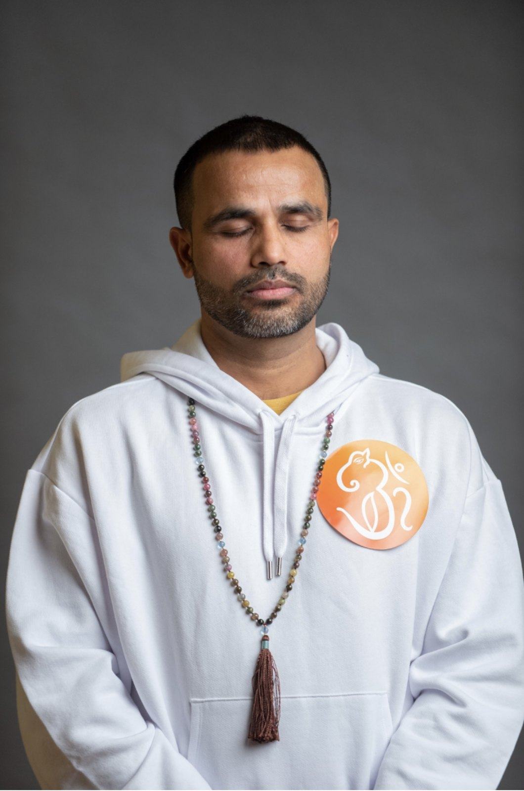 Yogi Ananda in meditation, wearing a mala and the Yoga House om