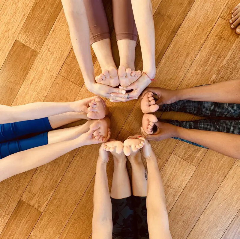 Hands holding feet in a circle on the studio floor