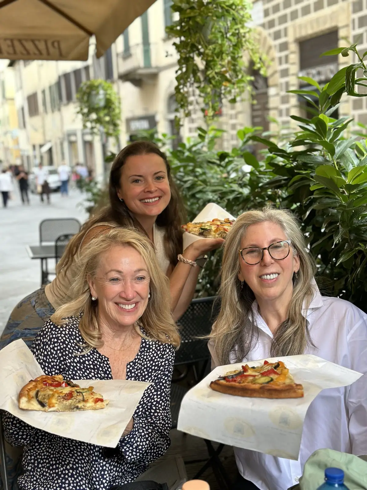 Three friends sharing pizza at a café in Florence