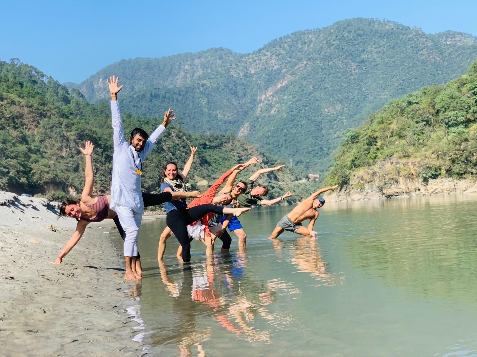 A joyful group stretching together in the shallows of the Ganga