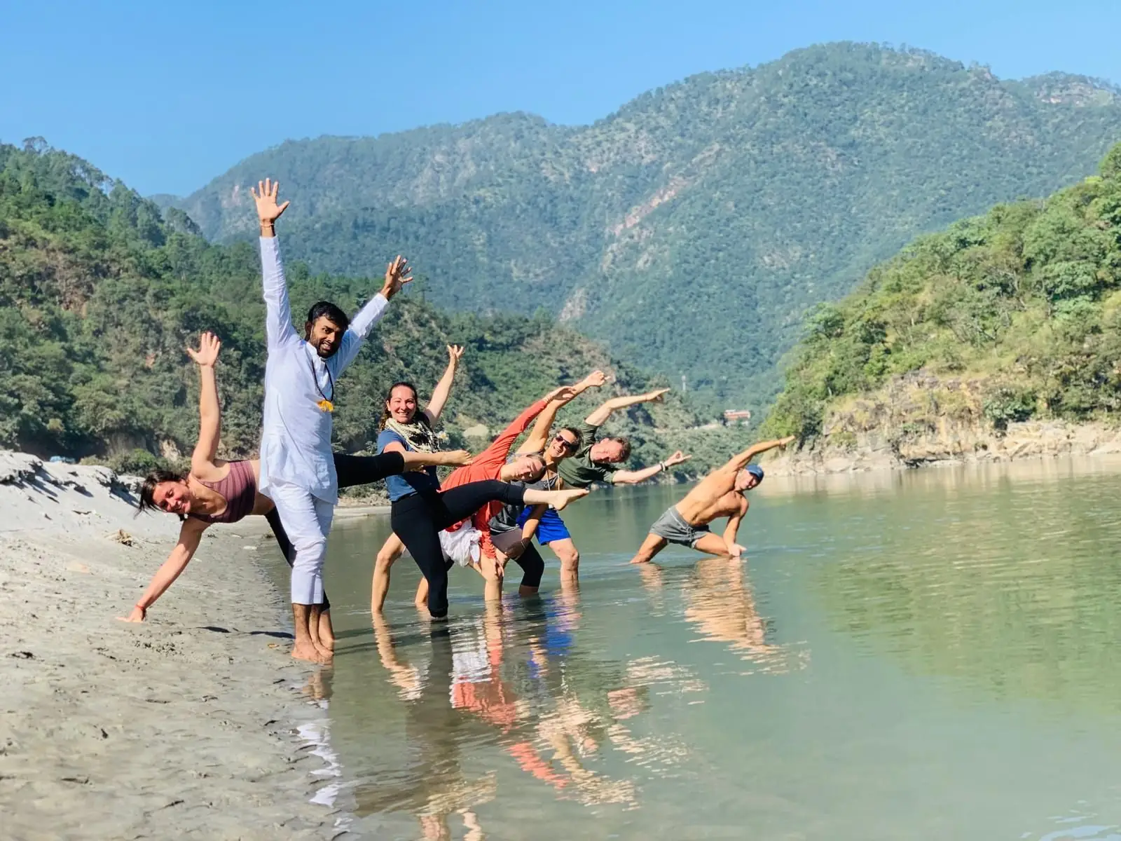 A joyful group stretching together in the shallows of the Ganga