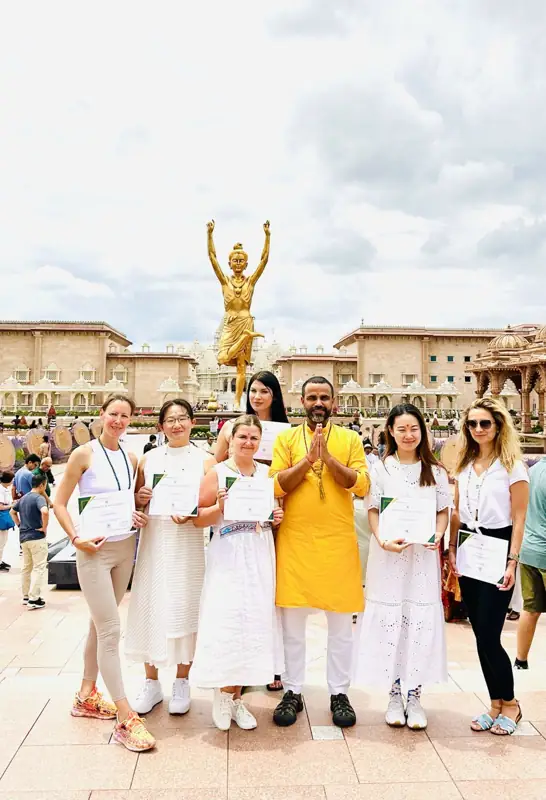 Graduates holding certificates beside their teacher at the temple
