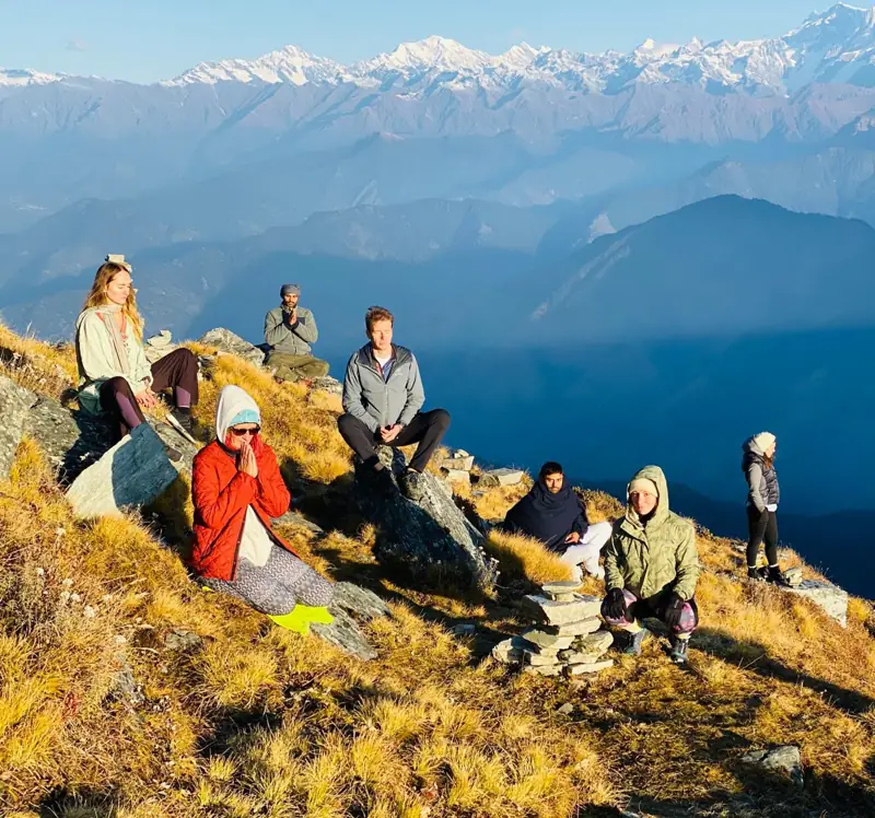 Students meditating facing the snow-capped Himalayas