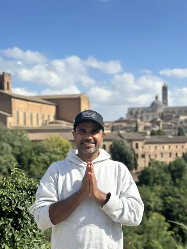 A teacher with hands in namaste, Siena cathedral behind