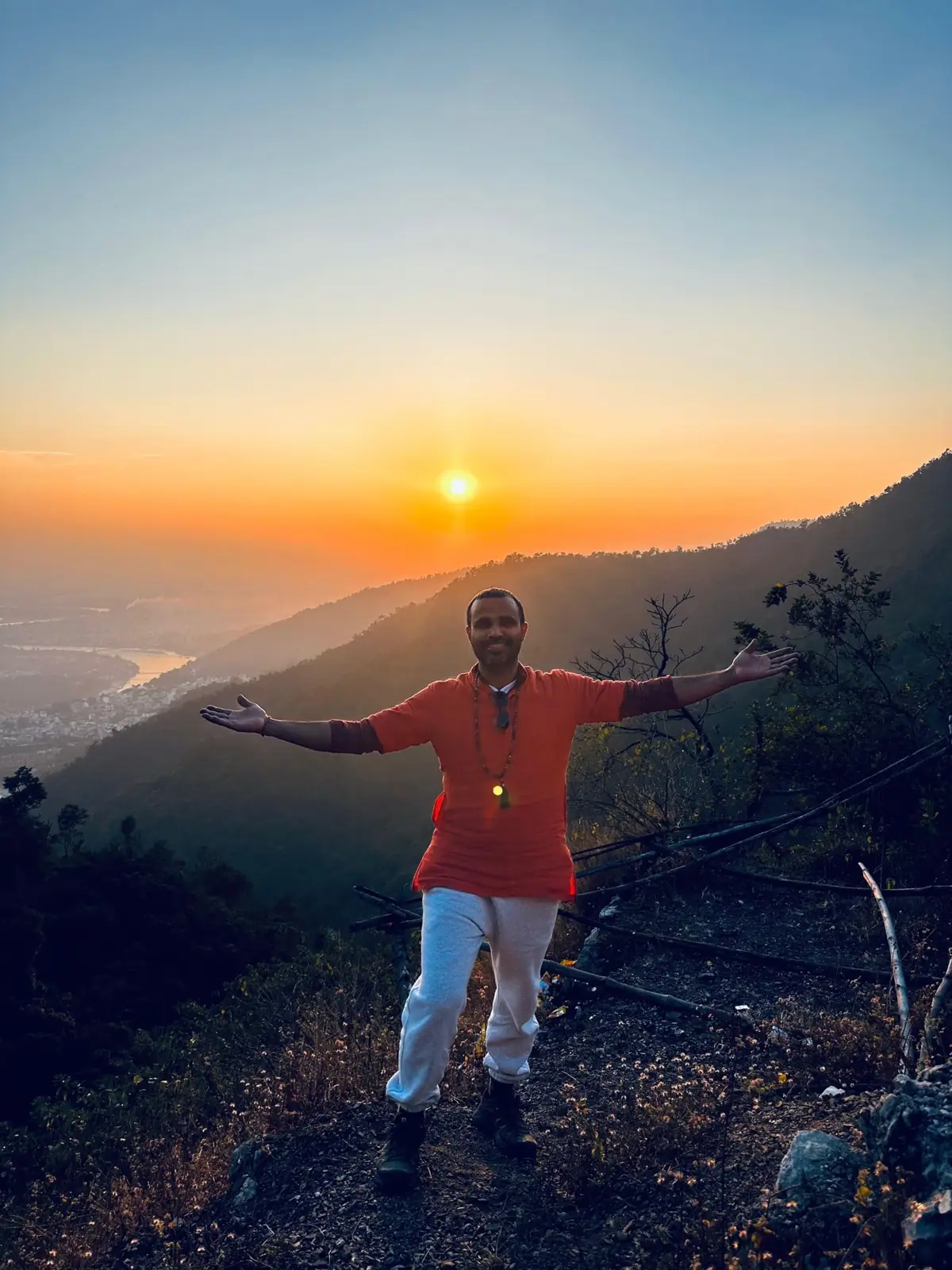 A teacher with arms wide open at sunrise above the Ganga valley