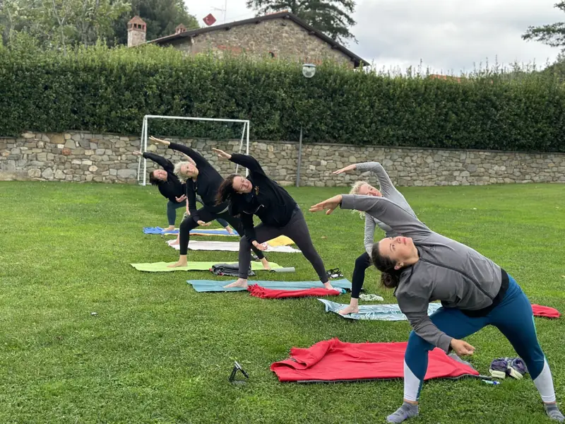 Students in side angle pose on the lawn beside a stone wall