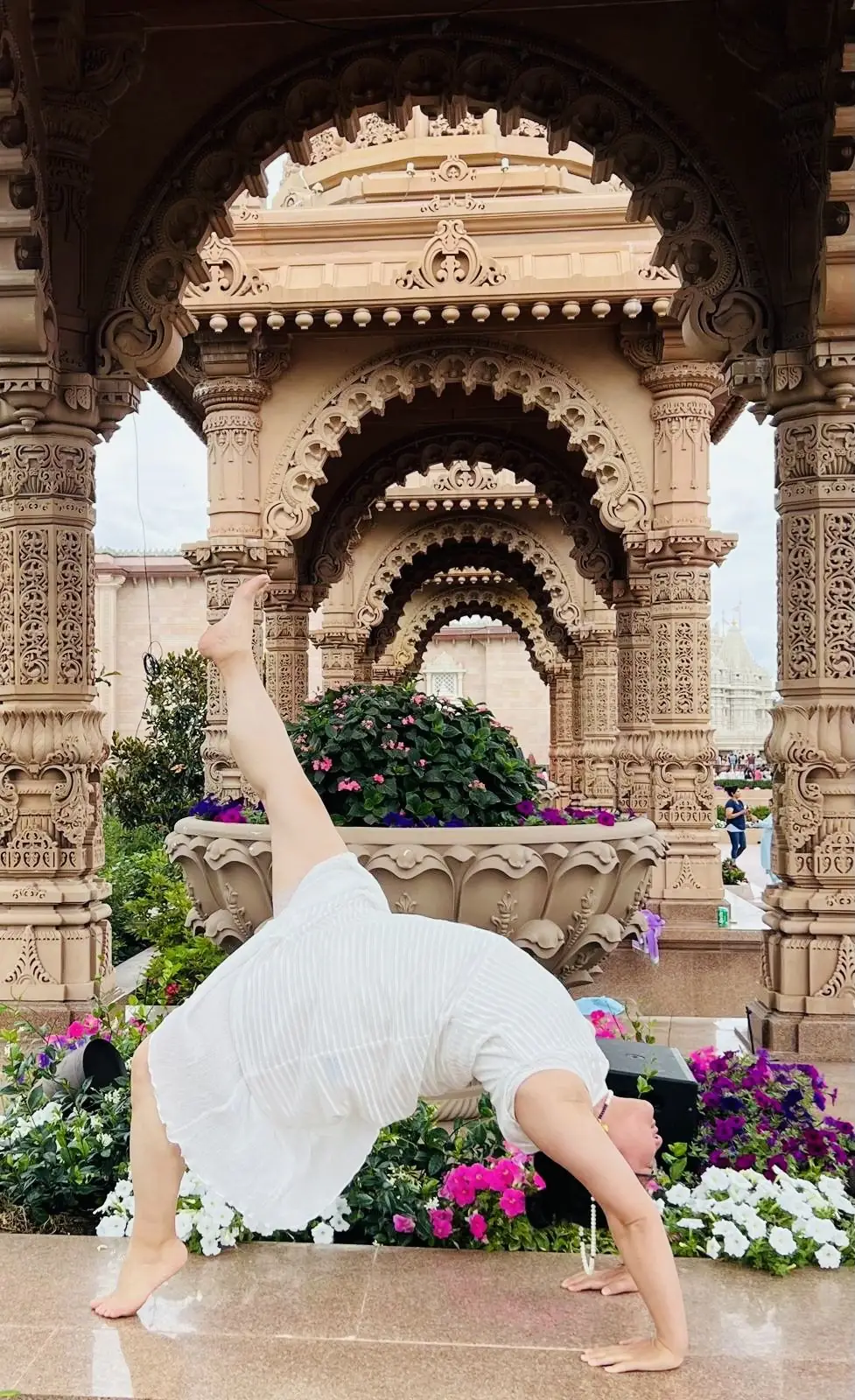 A wheel pose variation among carved temple pavilions and flowers